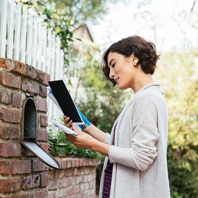 A woman checking mail received in her mailbox, demonstrating mail expertise powered by experience.