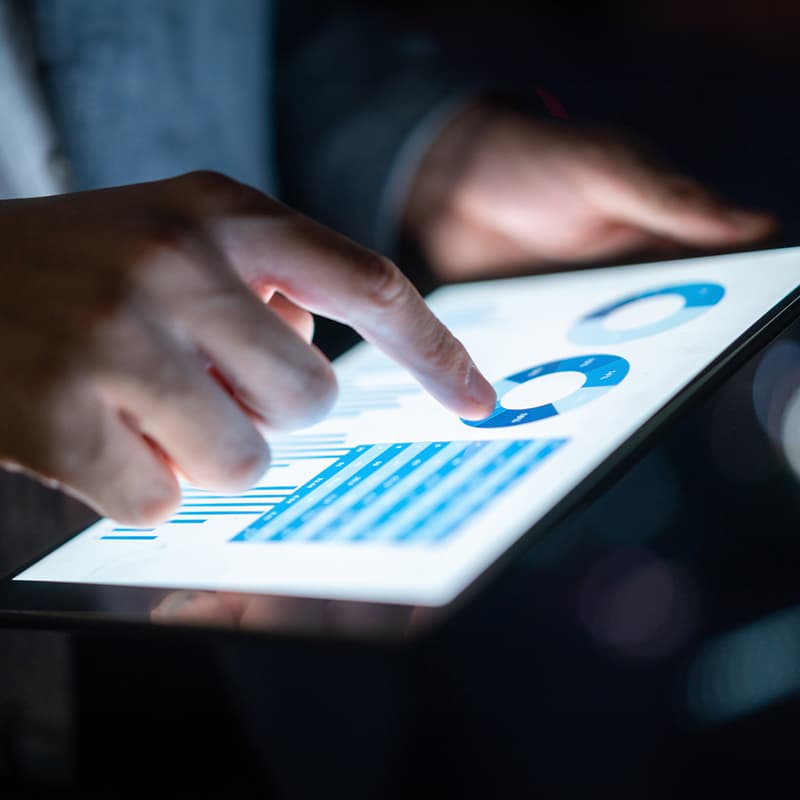 focus on a tablet with charts displayed and a hand working through them