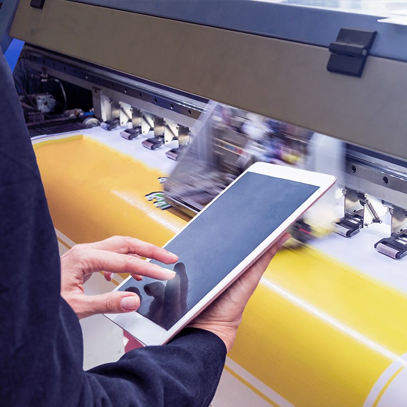 Technician touch control tablet on format inkjet printer during yellow vinyl