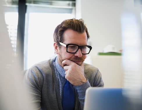 Focused businessman working at laptop hand on chin